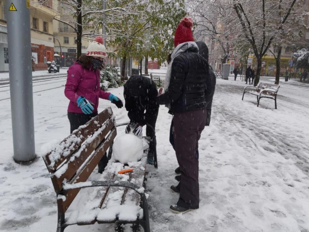 Un grupo de amigos prepara un muñeco de nieve en Gran Vía.