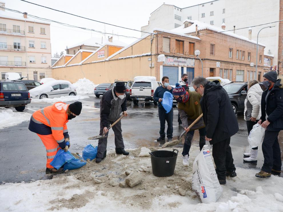 Un grupo de vecinos recoge la sal que reparte el Ayuntamiento de Teruel para prevenir la formación de hielo.