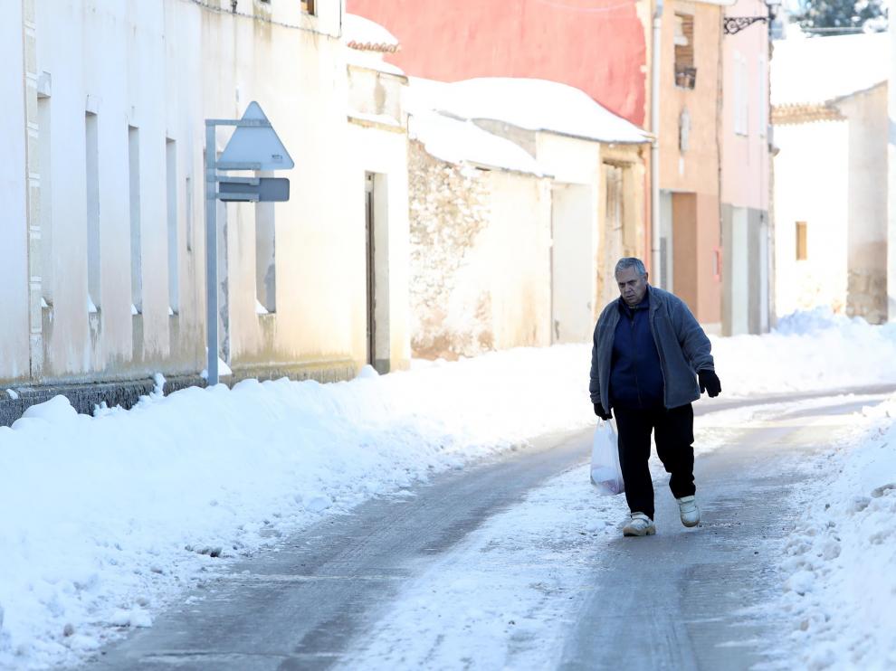 Un vecino camina por una calle de Bello cubierta de hielo.