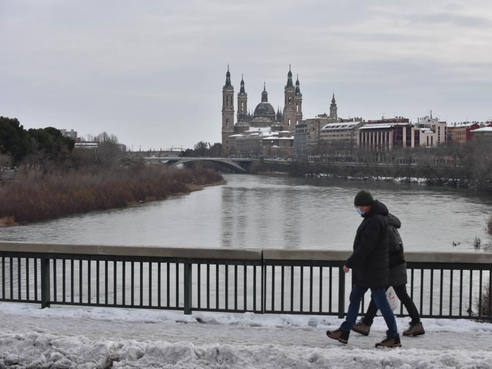 Una pareja camina entre la nieve del puente de Santiago.