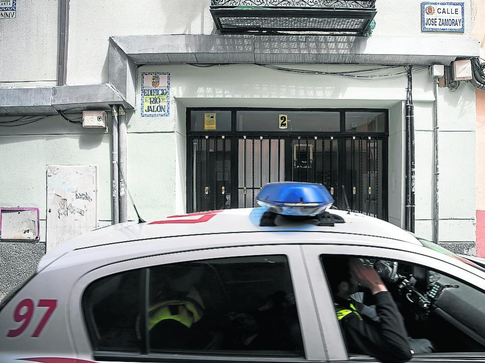Un coche patrulla pasa junto al portal donde se produjeron los hechos en la calle de Zamoray de Zaragoza