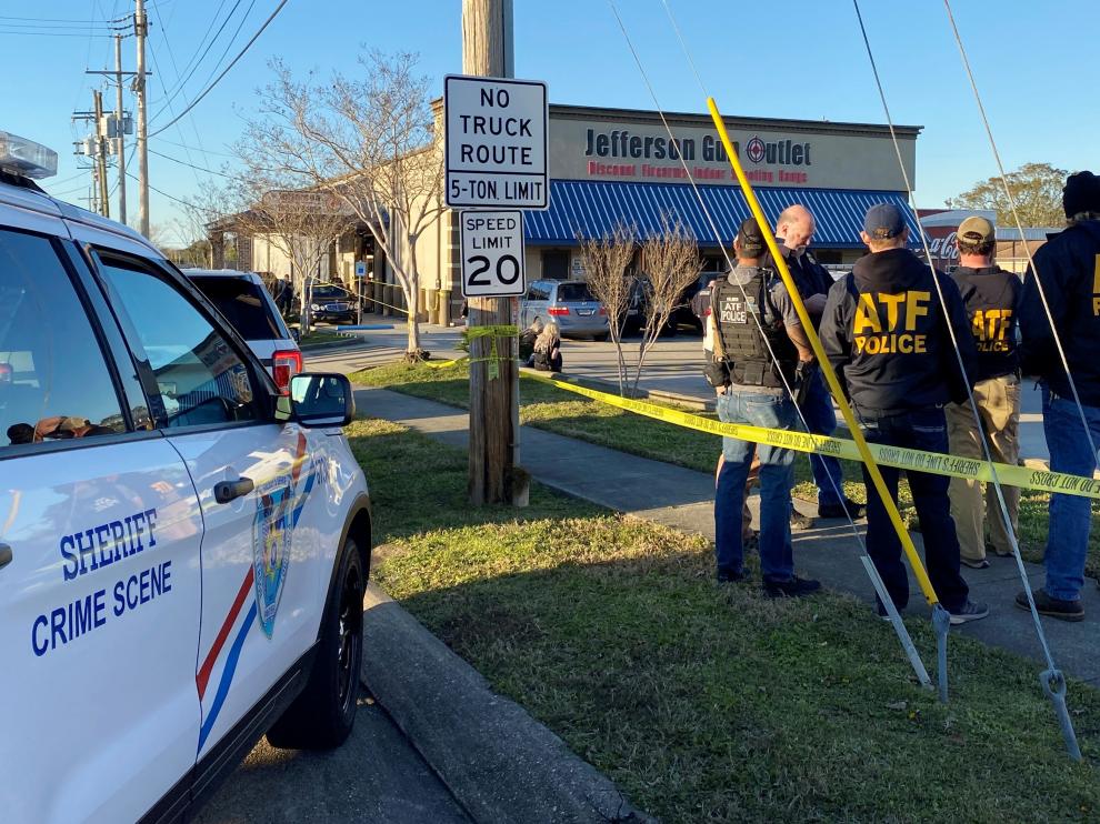 Law enforcement officers stand near the site of a shooting at a gun store in Metairie
