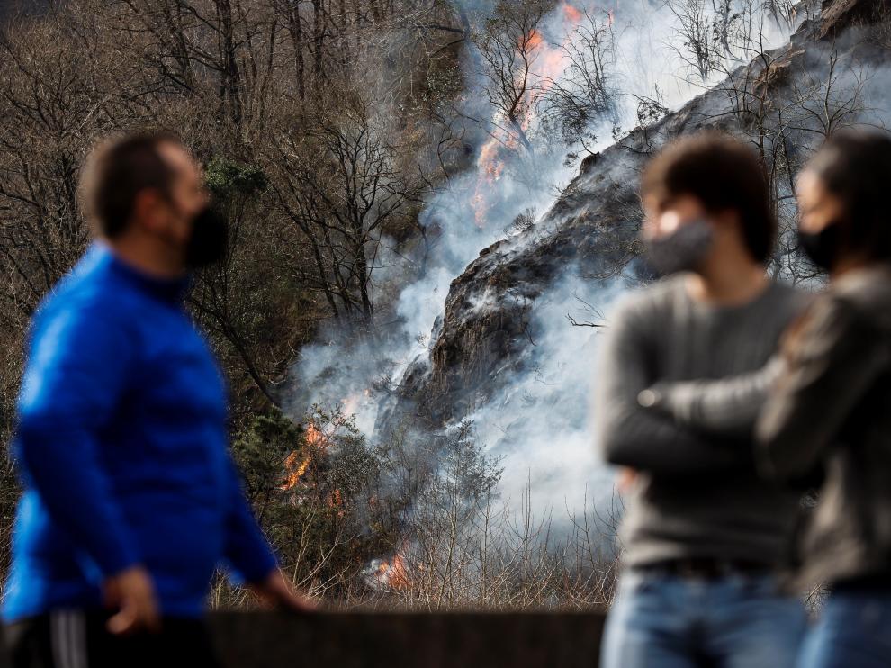 Varias personas observan este domingo en Endarlatsa (Guipúzcoa) un foco del incendio forestal.