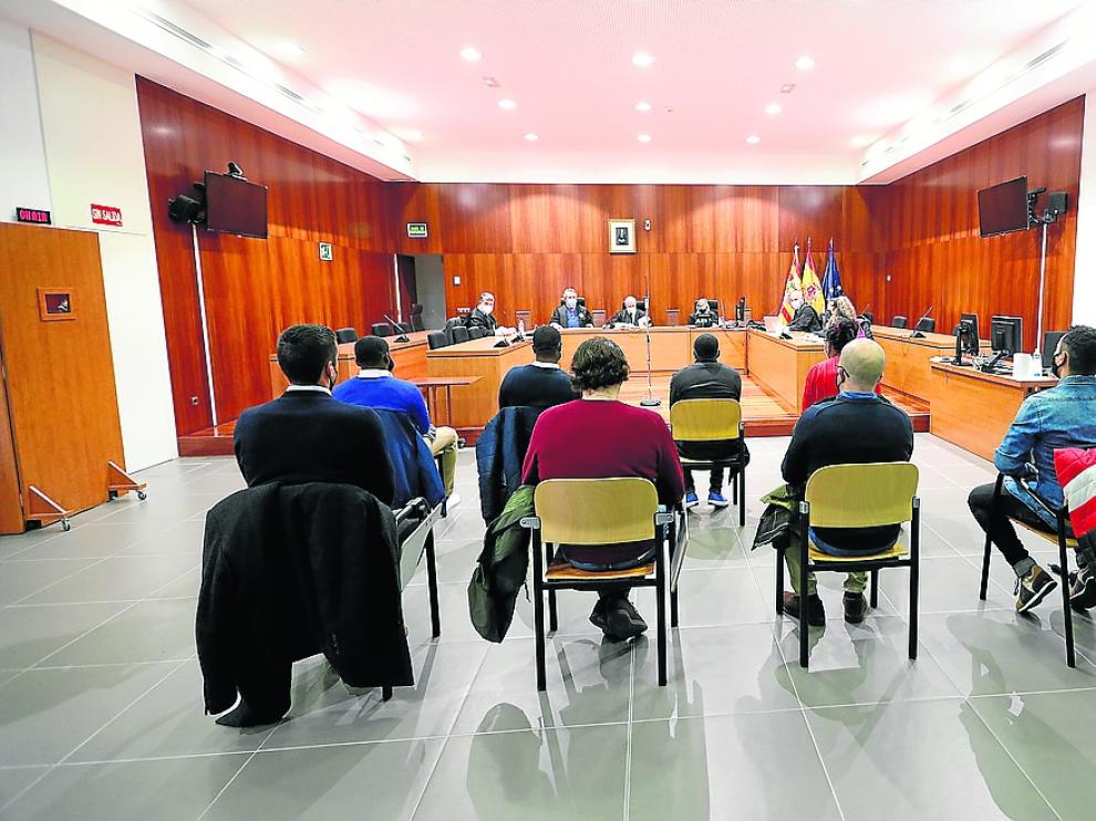 La dueña del bar y los tres clientes, en primera fila frente al tribunal, seguidos de los agentes.