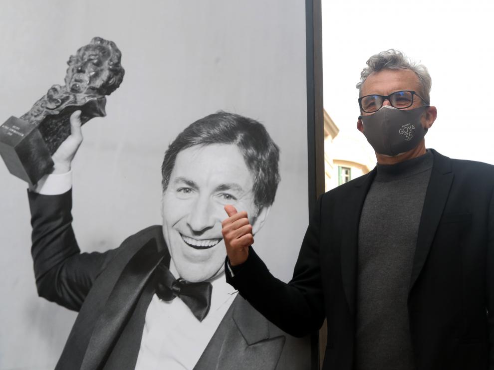 El presidente de la Academia de Cine, Mariano Barroso, junto a una foto de una exposición en Málaga que celebra la gala de los Goya.