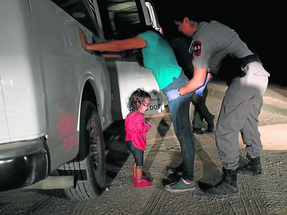 Una pequeña llora mientras su madre es registrada por una agente