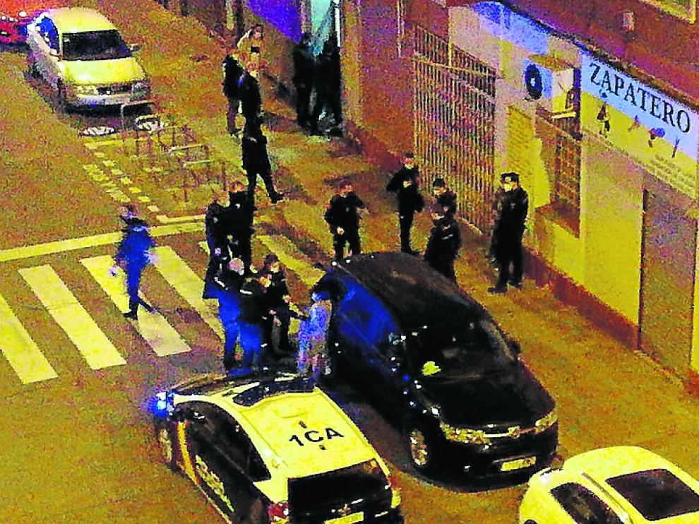 La detenida, entre el vehículo negro y un coche patrulla