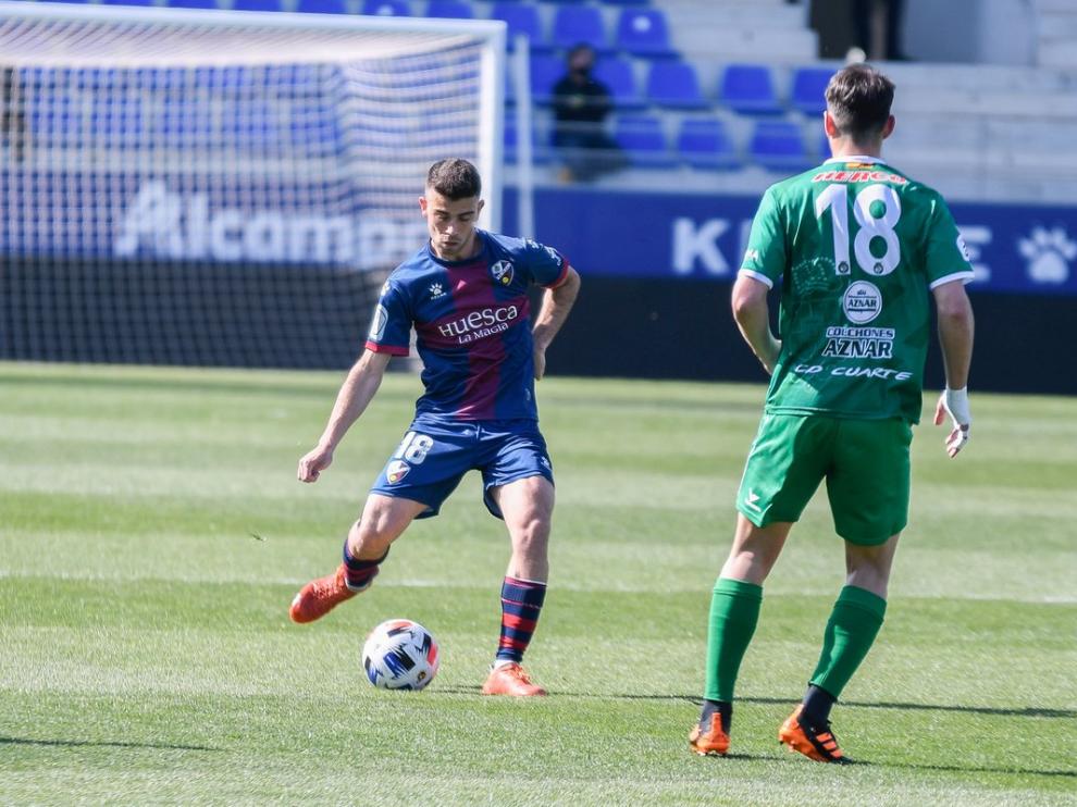 Carrasco, del Huesca, realiza un pase ante la presión de Andreu, del Cuarte.