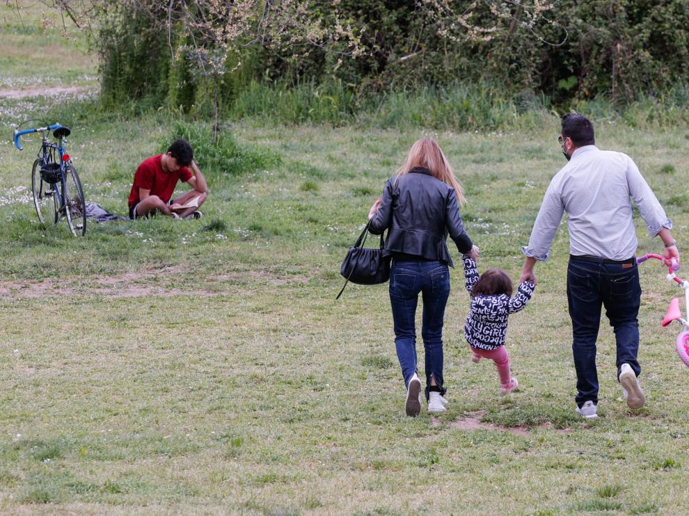 Unos padres pasean con su hija por un parque de Roma.