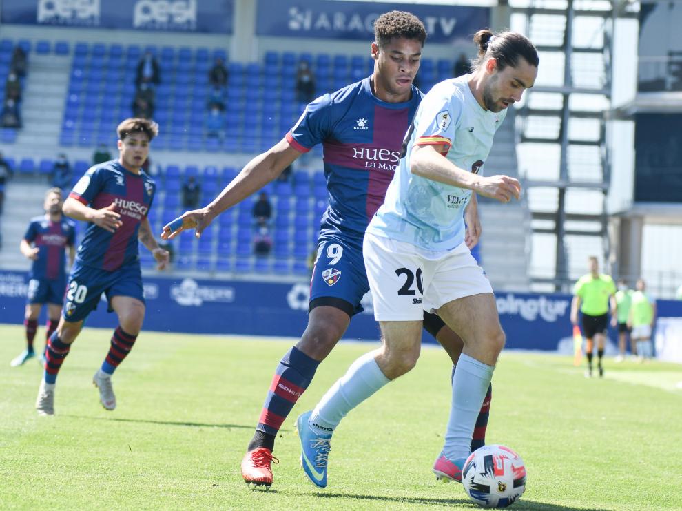 Barba, del Brea, protege el balón ante la presión de Carlos Kevin, del Huesca B.