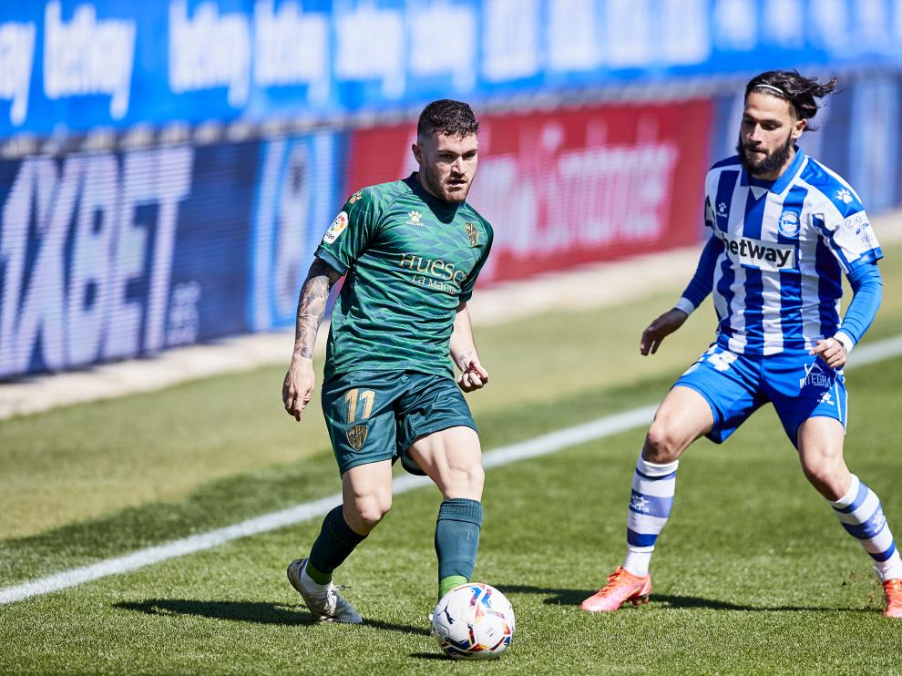 Javi Galán, de la SD Huesca, conduce el balón frente a Jota, del Alavés.