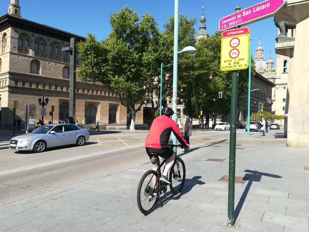 Un ciclista, este viernes, a su paso por la nueva señal que obliga a transitar a pie por el cruce del puente de Piedra.