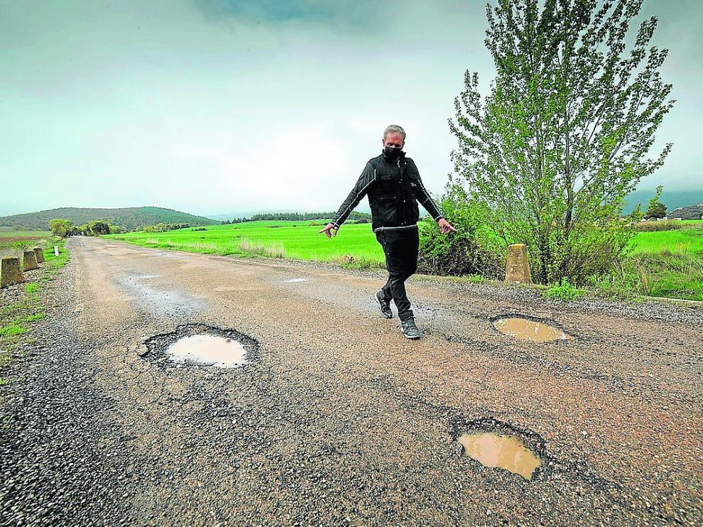 El alcalde de Luesma señala los baches que presenta la carretera A-1506.