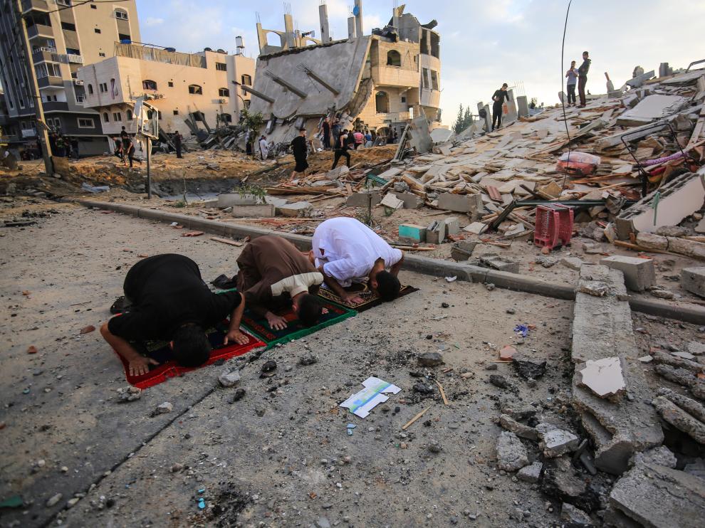 Tres hombres rezan en medio del caos tras un bombardeo israelí en Gaza