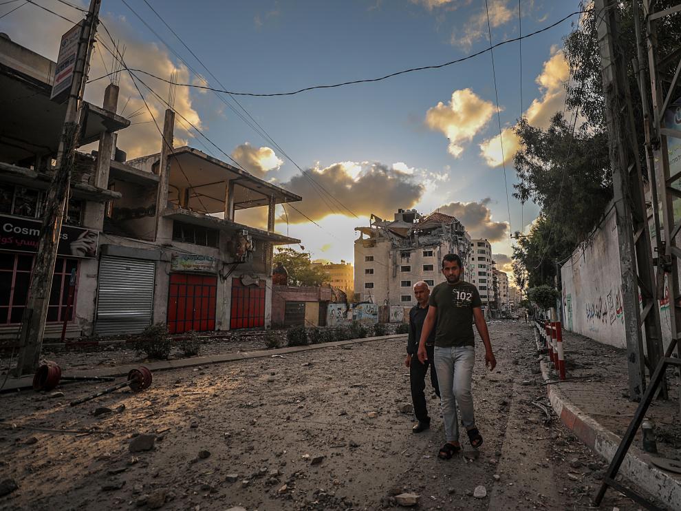 Dos palestinos caminan por una calle de Gaza, destrozada por los bombardeos israelíes