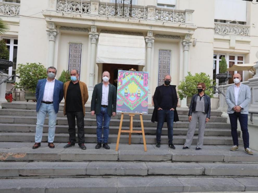 Representantes de las entidades que organizan y patrocinan el Festival de Cine de Huesca en la escalera del Casino junto al cartel de la edición de 2021
