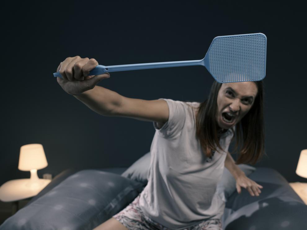 Mujer intentando matar moscas y mosquitos para poder dormir