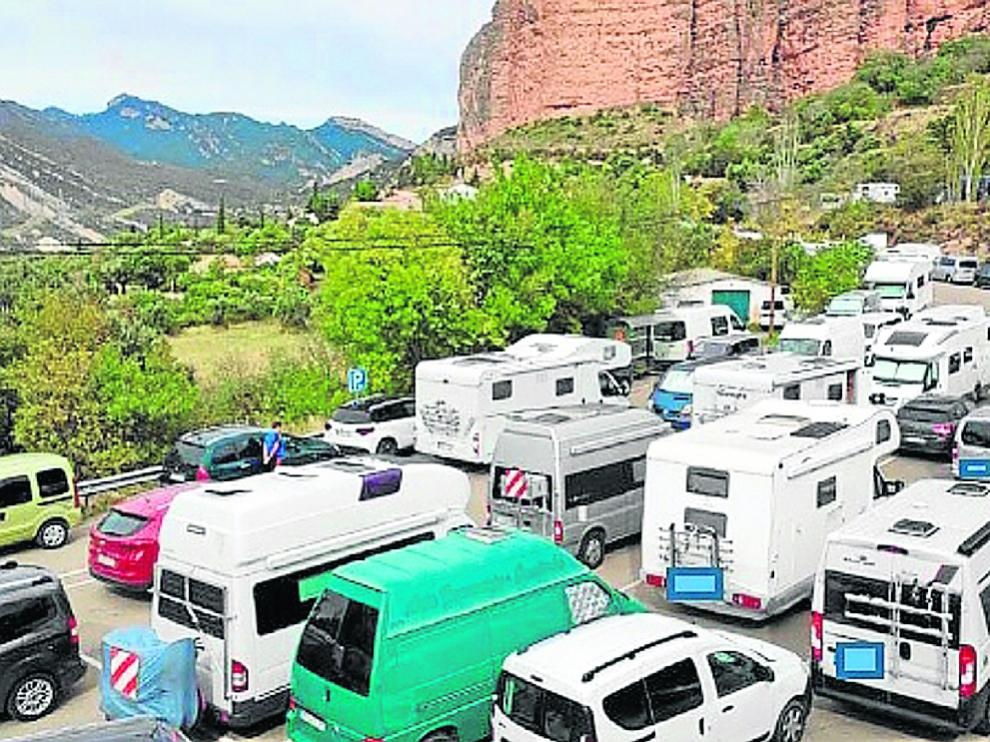 Zona de aparcamiento reservada para autobuses ocupada por turismos y caravanas en Riglos