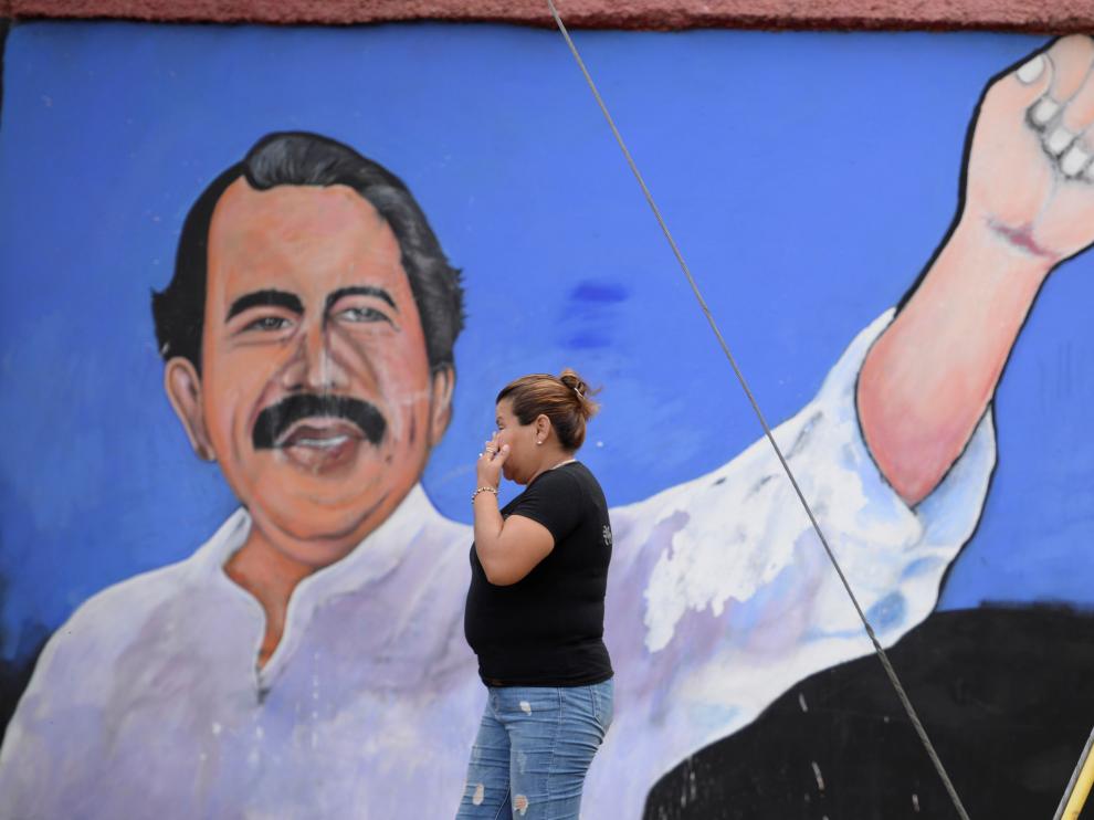 Una mujer pasa por un muro en el que está pintado Ortega.