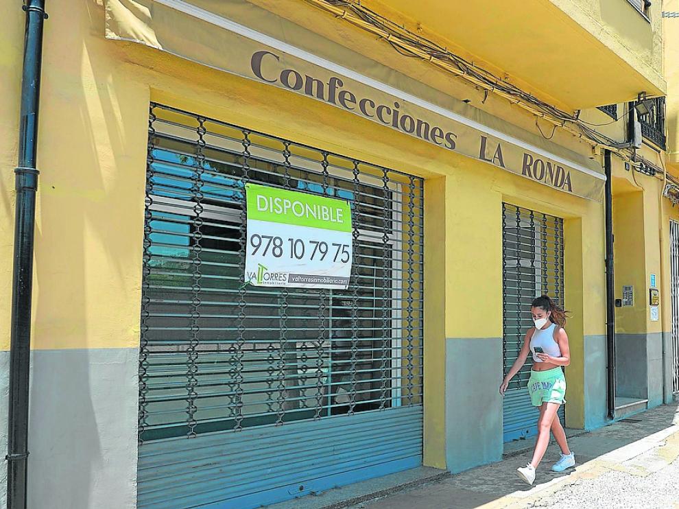 Locales comerciales cerrados en un tramo de la Ronda de Ambeles con el pavimento parcheado