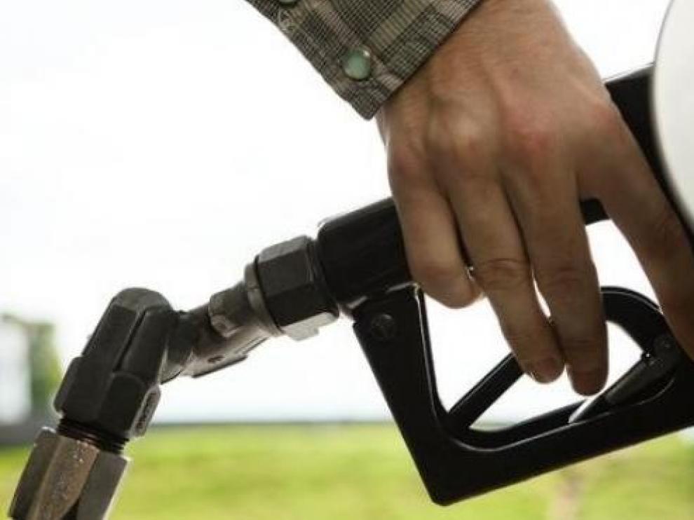 Una persona echando combustible en una gasolinera.
