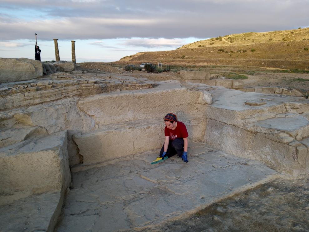 Una estudiante que participa en la excavación limpia los restos de la cantera de piedra encontrada en Los Bañales.