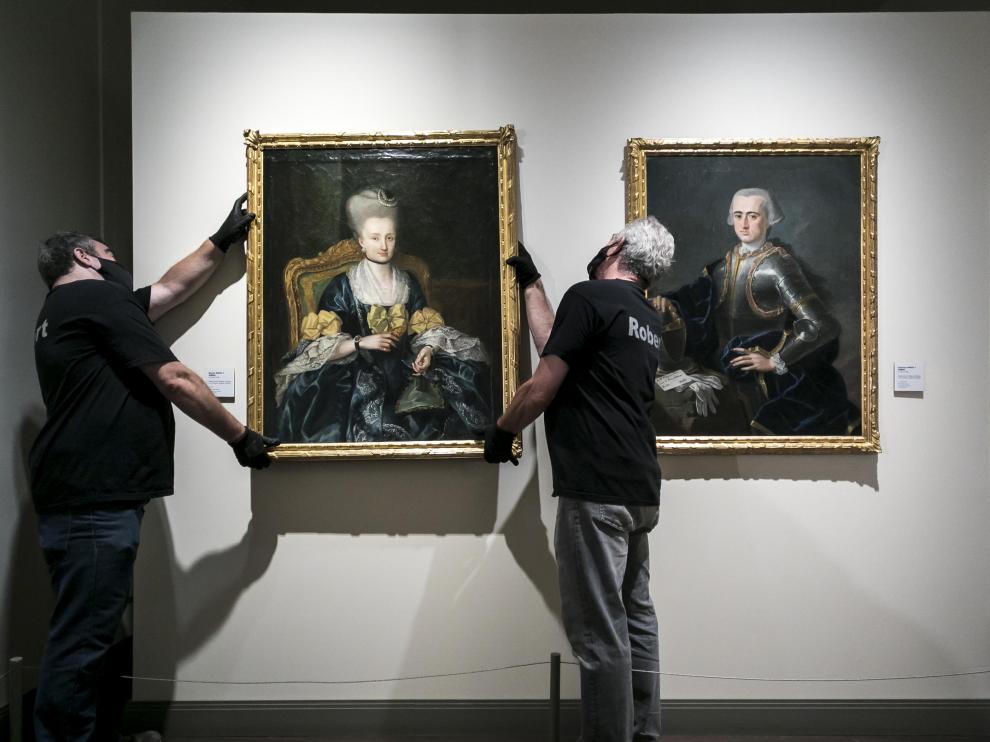 Dos operarios cuelgan el segundo de los retratos en su emplazamiento actual, en la Sala Goya del museo.