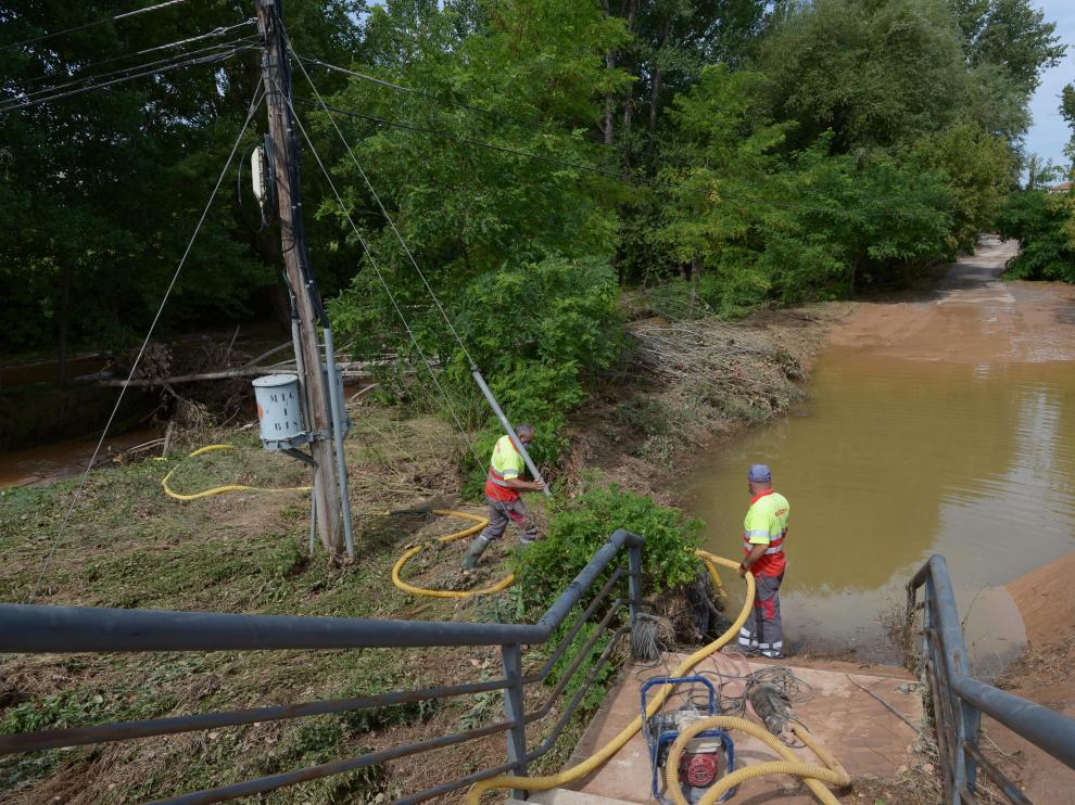 Los bomberos achican agua con bombas para reabrir el acceso a la ribera del Turia.