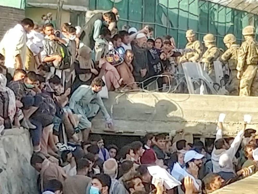 Security personnel assist with evacuation of people waiting outside the airport in Kabul