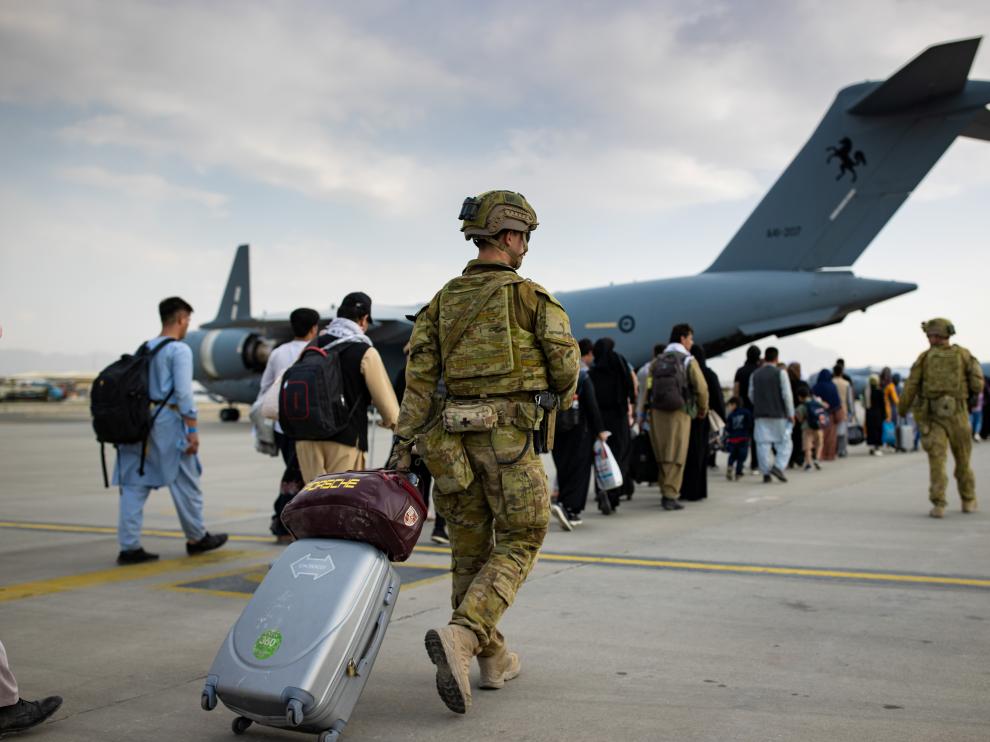 Australian citizens and visa holders prepare to board the Royal Australian Air Force C-17A Globemaster III aircraft, as Australian Army infantry personnel provide security and assist with cargo, at Hamid Karzai Internati