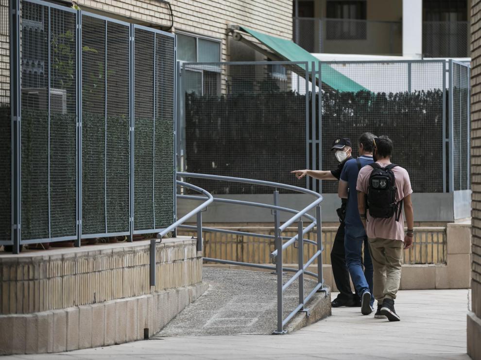 Tres agentes entran en el portal de la vivienda donde ocurrió la agresión.