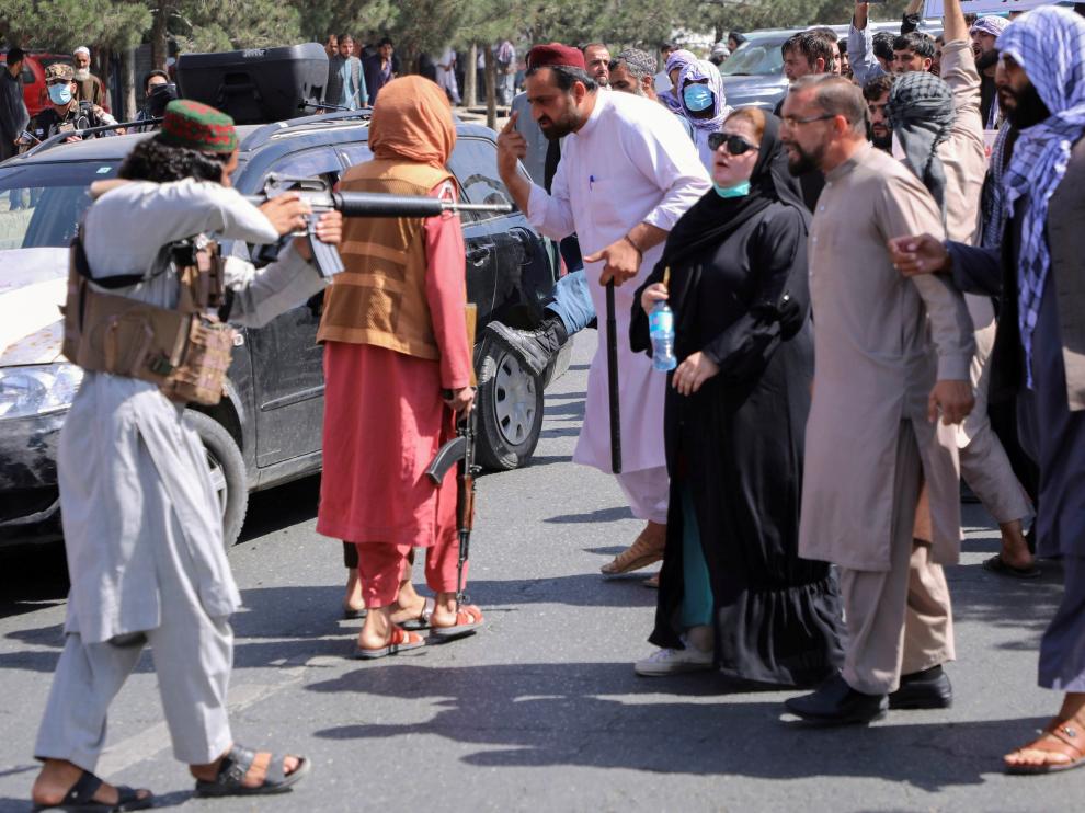 A member of the Taliban forces points his gun at protesters, as Afghan demonstrators shout slogans during an anti-Pakistan protest, near the Pakistan embassy in Kabul, Afghanistan