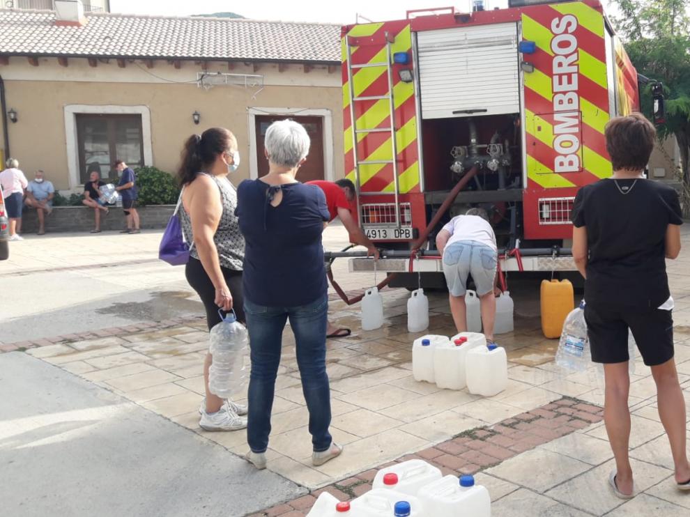 Vecinos de Laguarres hacen cola para llenar de agua sus garrafas en el camión de bomberos.