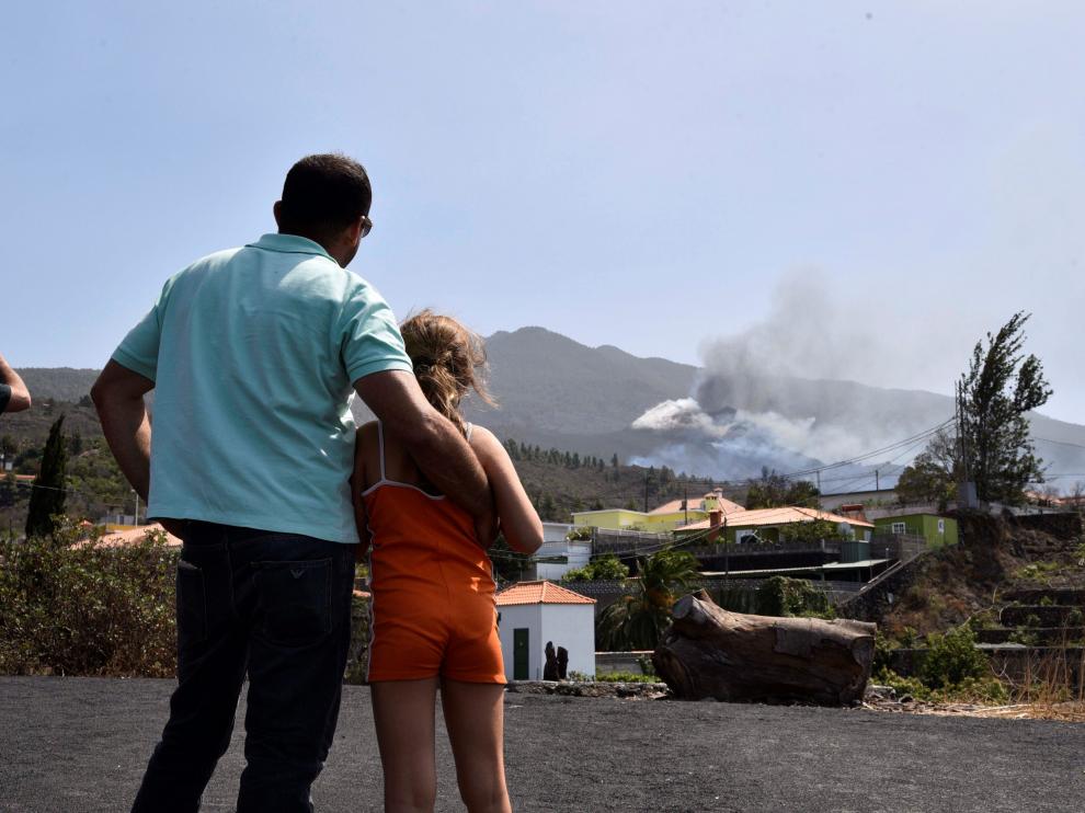 Un padre y su hija observan cómo la última colada toma contacto con la primera que emergió del volcán de Cumbre Vieja.