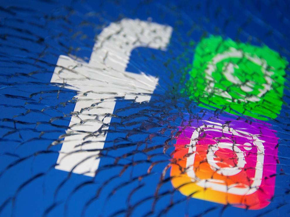 Facebook, Whatsapp and Instagram logos are displayed through broken glass in this illustration