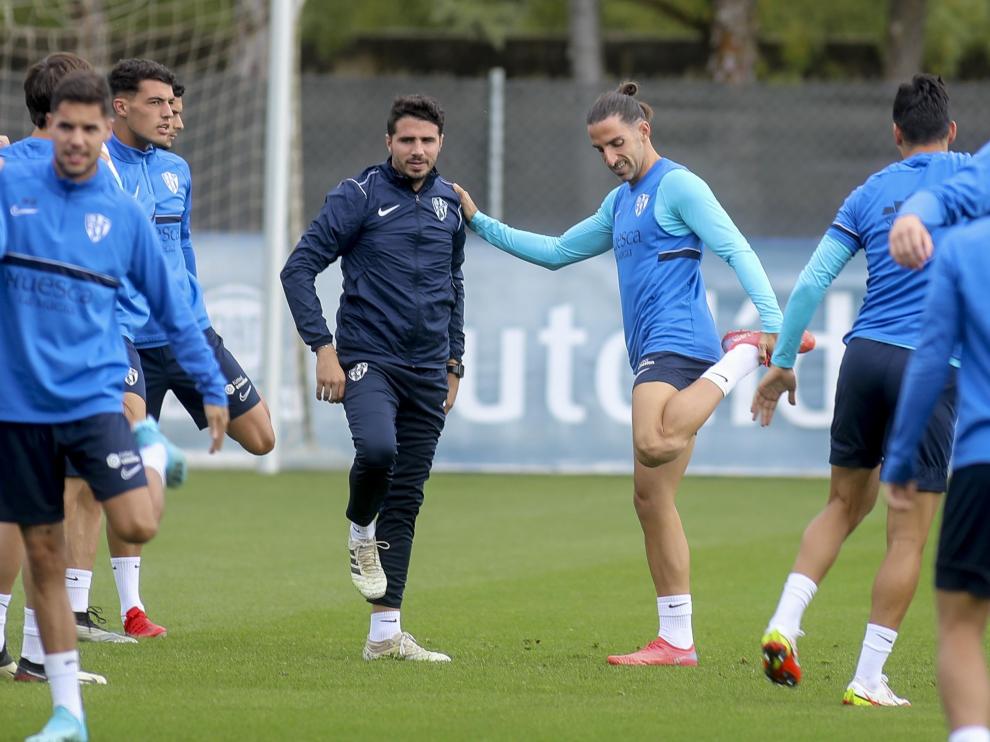 Marc Mateu se apoya en el asistente Adrián Sipán para realizar un estiramiento durante el entrenamiento de la SD Huesca de este martes.