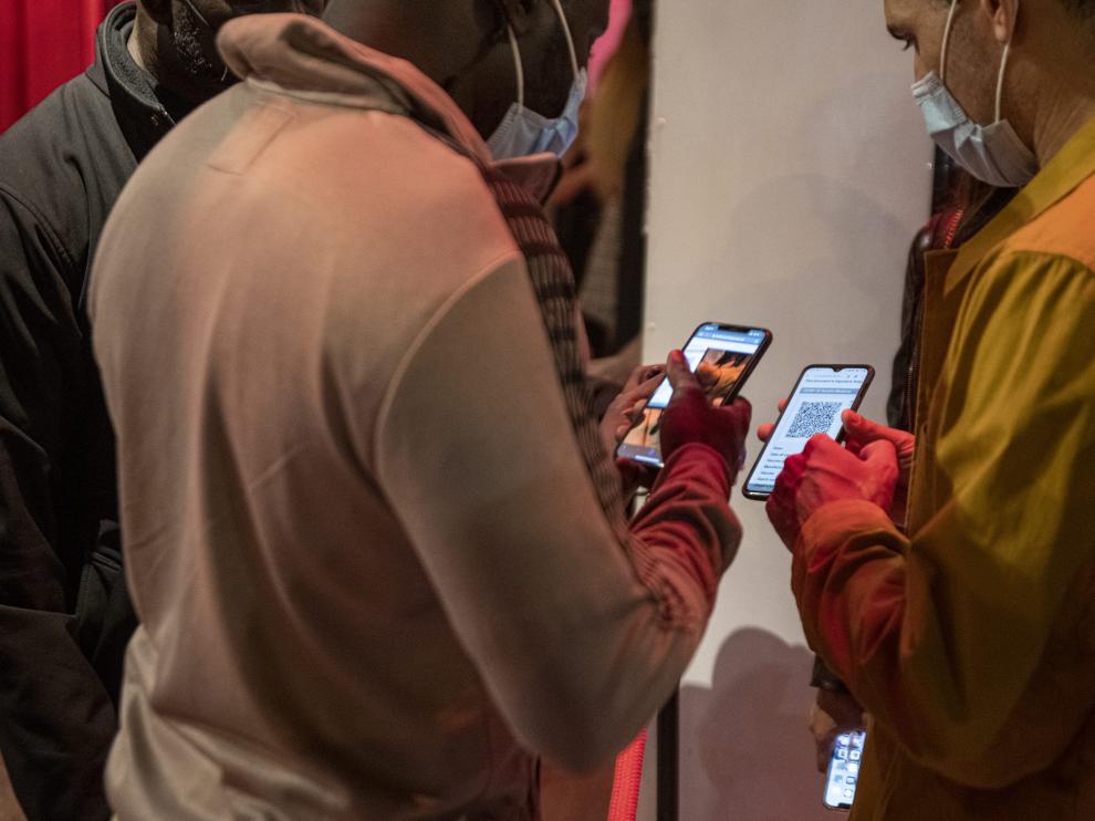 Una persona muestra su pasaporte covid en la entrada de una discoteca.