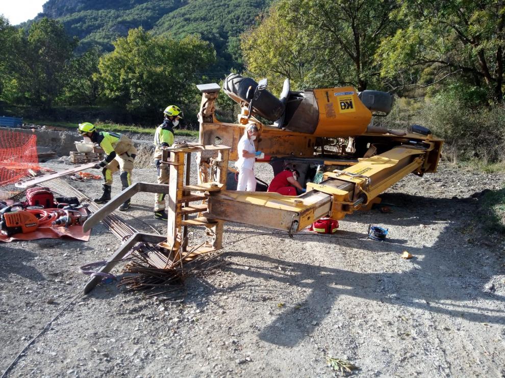 Labores de rescate del trabajador atrapado bajo la excavadora volcada en Benasque.