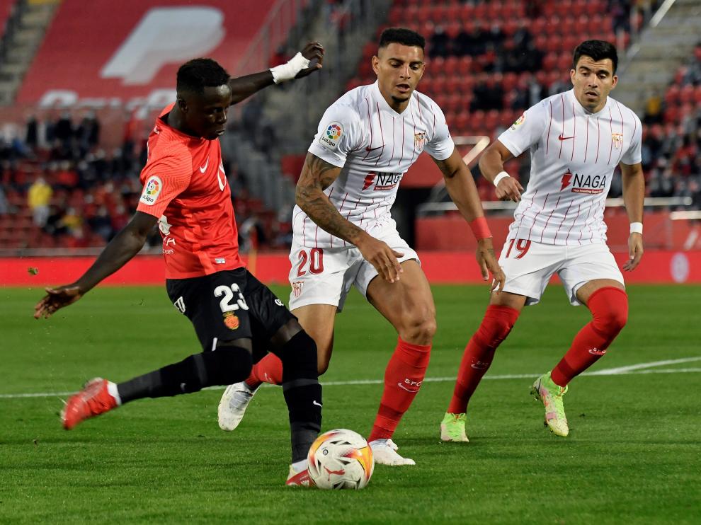 El delantero senegalés del Mallorca, Amath Ndiaye, disputa un balón con Diego Carlos y Marcos Acuña, defensas del Sevilla.
