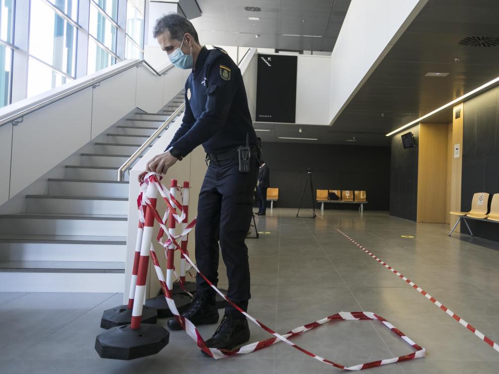 Un policía recoge el precinto de seguridad colocado en la puerta de la sala mientras declaraba el detenido