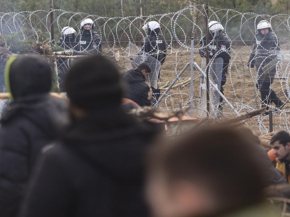 Soldados polacos observan desde su lado de la frontera a los refugiados y migrantes que reciben ayuda humanitaria en un campo en la frontera con Polonia en la región de Grodno.