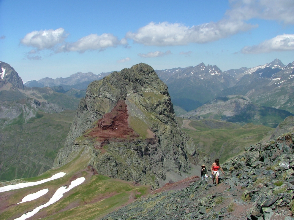 Cumbre del Anayet, vista desde el falso Anayet. Al fondo se ven las capas rojas del Pérmico cortadas por el pitón volcánico. La excursionista está llegando a la cumbre del falso Anayet donde, intercalada en las capas rojas, hay una colada volcánica de las que emitió el pitón del Anayet