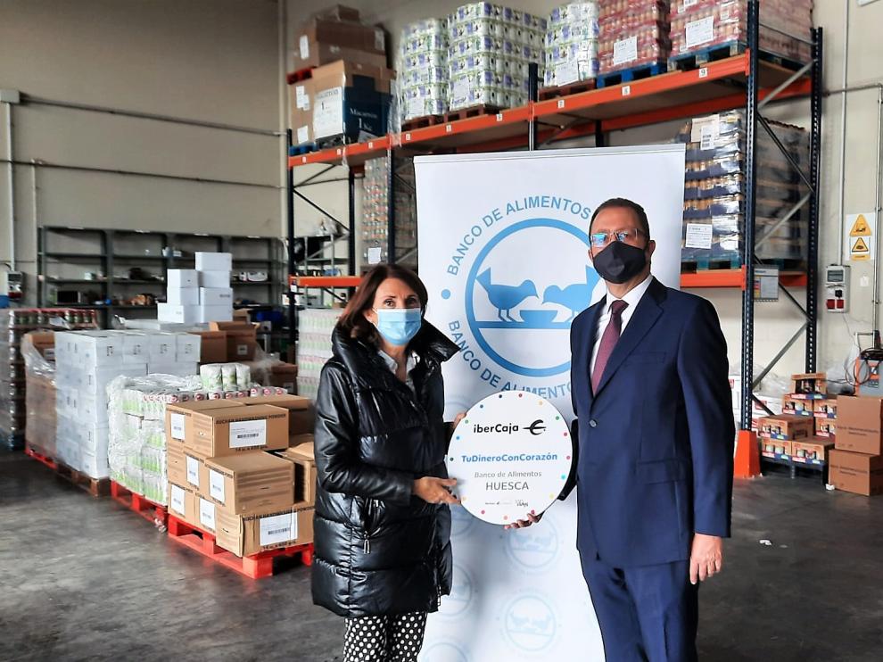 El director provincial de Ibercaja en Huesca, Jesús Beamonte, entrega la donación a la presidenta del Banco de Alimentos de Huesca, Julia Lera
