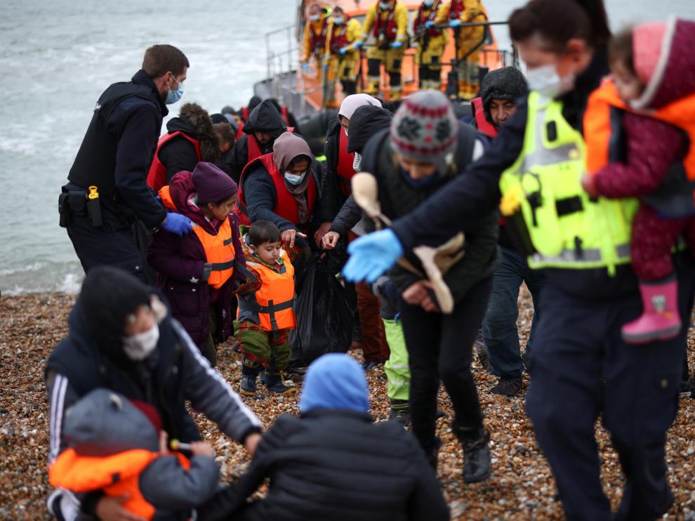 Migrants are brought ashore by RNLI Lifeboat staff, police officers and Border Force staff, after having crossed the channel, in Dungeness