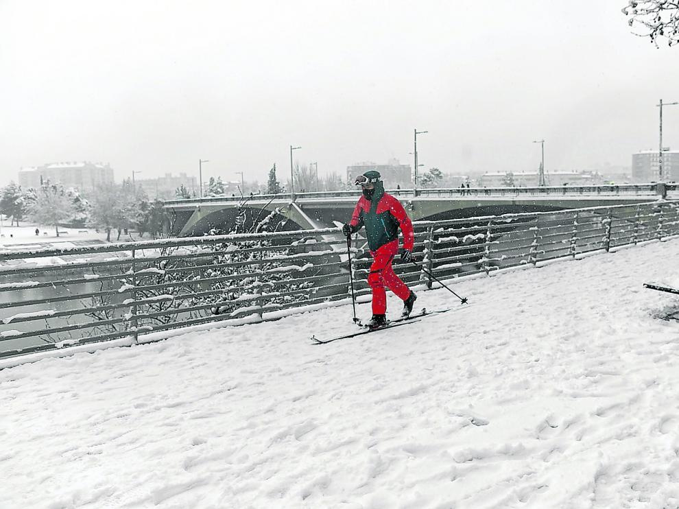 Contra los desmanes de Filomena, imaginación: un joven improvisa una pista de nieve a orillas del Ebro y el puente de Santiago.