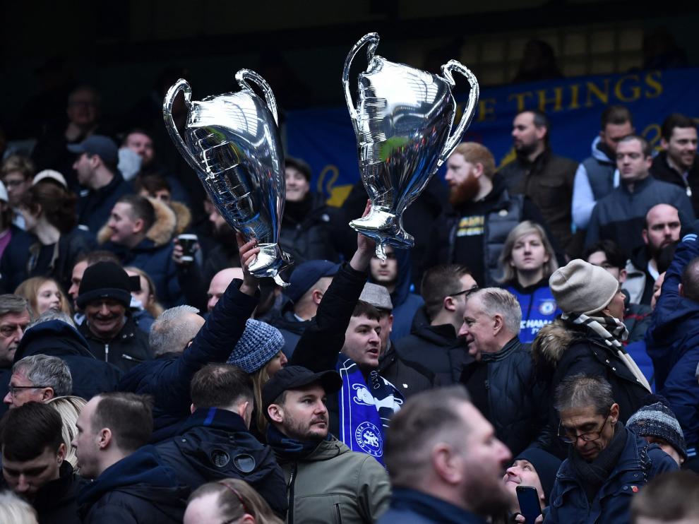 Dos aficionados sostienen globos con la forma del trofeo de la Liga de Campeones tras un partido.
