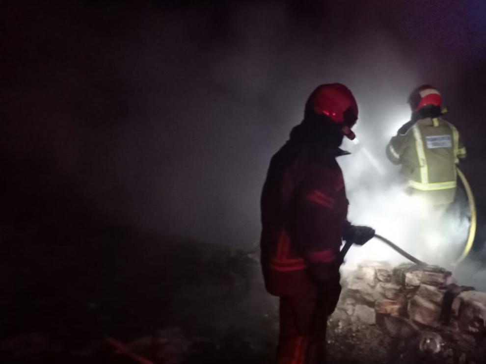 Dos bomberos, trabajando en la extinción del incendio, que se declaró por la noche.