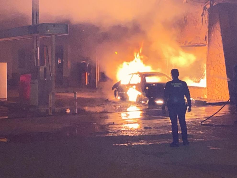La Guardia Civil intenta apagar el coche incendiado en la gasolinera