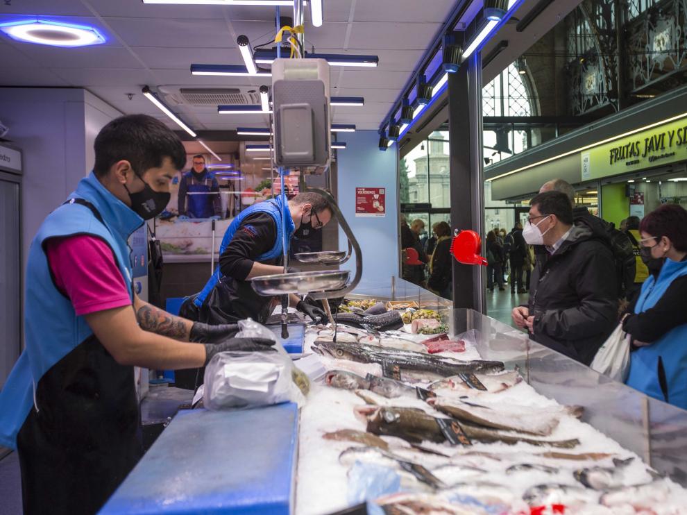 Pedro Huerta y uno de sus empleados, ayer, atendiendo a unos clientes en el Mercado Central.