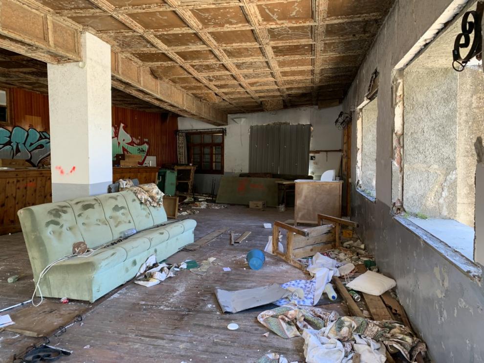 Una de las estancias principales del balneario, donde se observan ventanas arrancadas, pintadas, muebles viejos y basura.